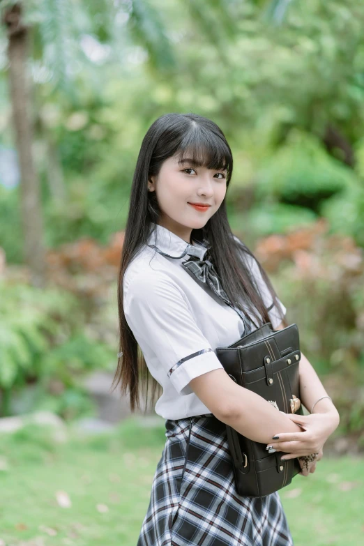 a young woman is standing in a plaid skirt with her hand on a bag