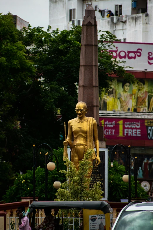 a large gold statue in front of the indian temple