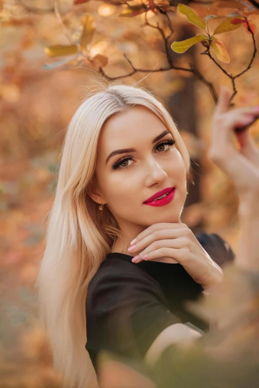 beautiful woman in black shirt posing with fall foliage