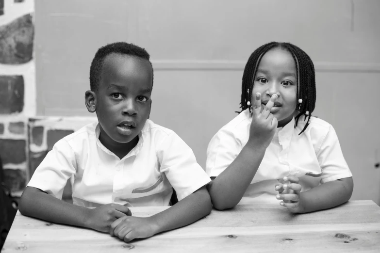 two children sitting at a table eating soing off the table