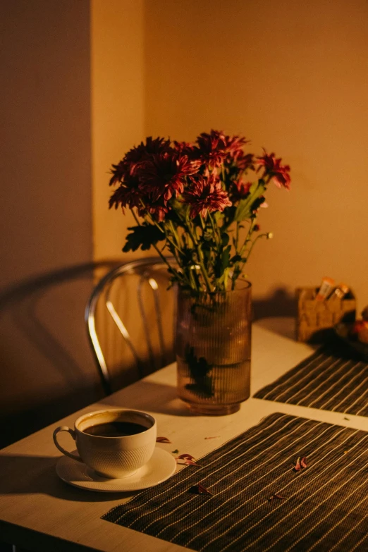 a table topped with a cup of coffee next to a vase filled with flowers