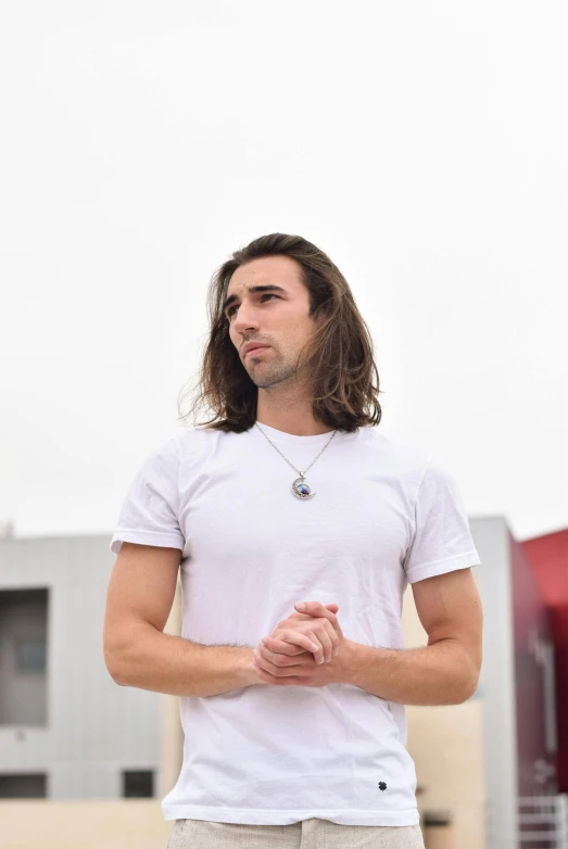 a man with long hair wearing white shirt and khaki shorts