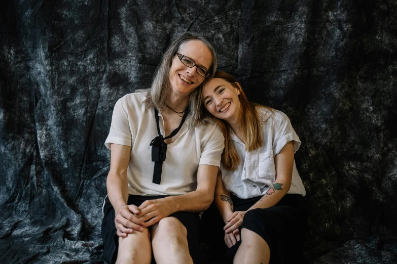 two women sitting together on a chair smiling