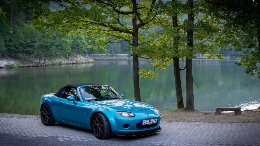 a blue car sitting on a street next to water