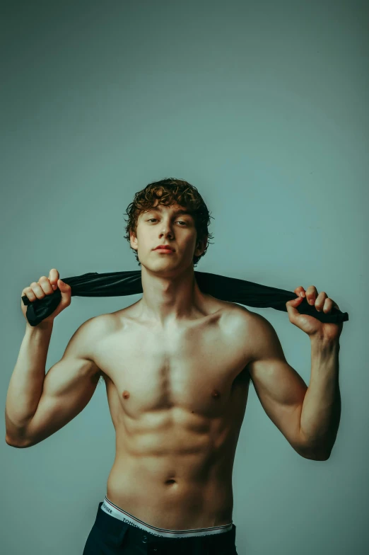 a young man holding two pairs of ties around his neck