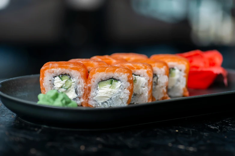 there is sushi rolls on a black plate with lettuce