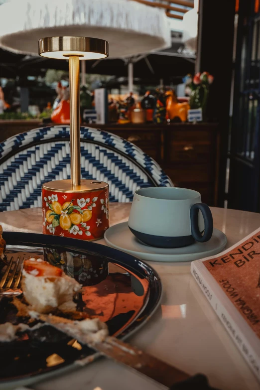 a lamp, coffee cup and book on a table