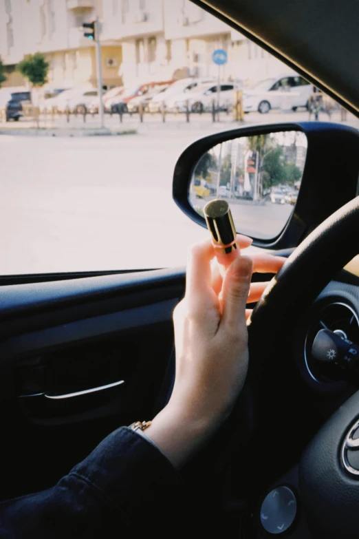 a woman is driving in her car holding a cellphone