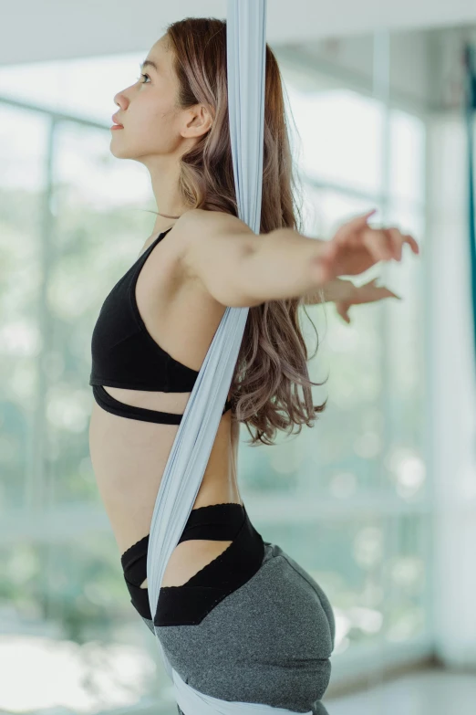 a woman performing aerial yoga poses with a white ribbon on her head