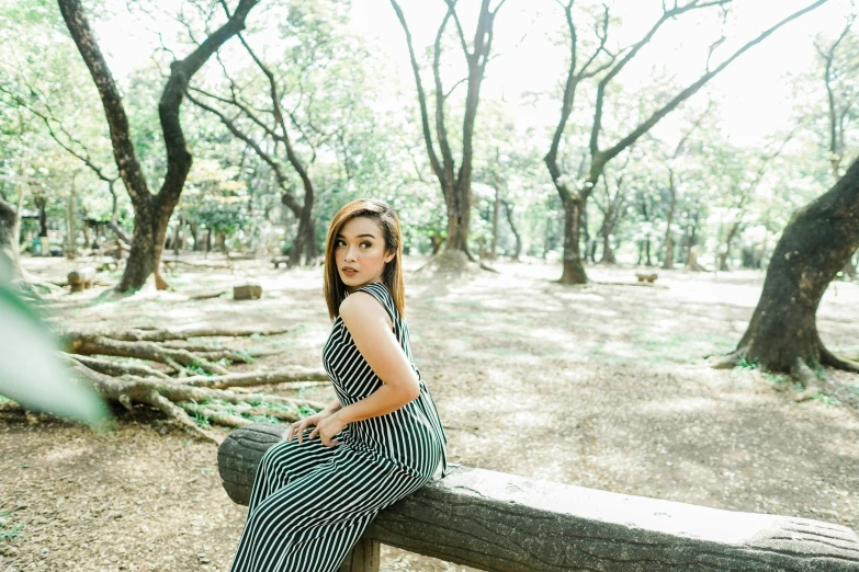 a woman sits on top of a log in a park