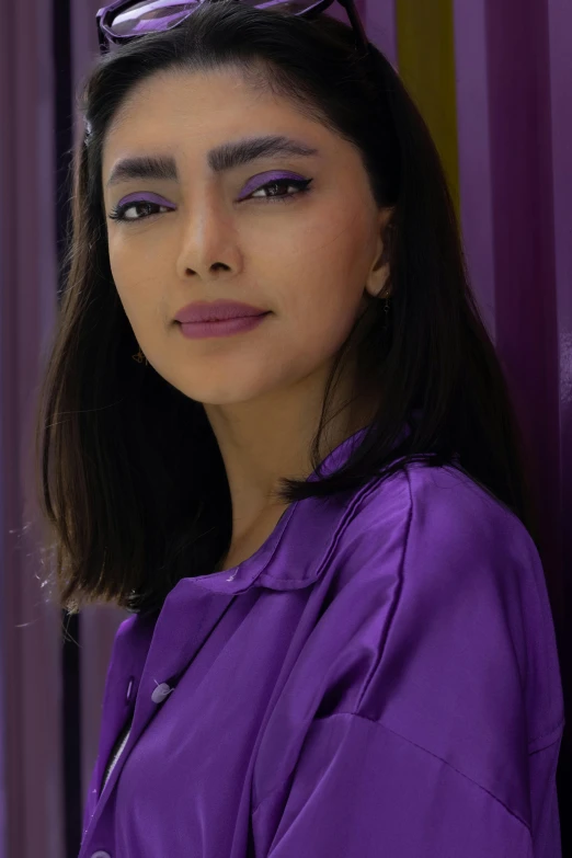 a girl wearing purple glasses poses in front of striped walls