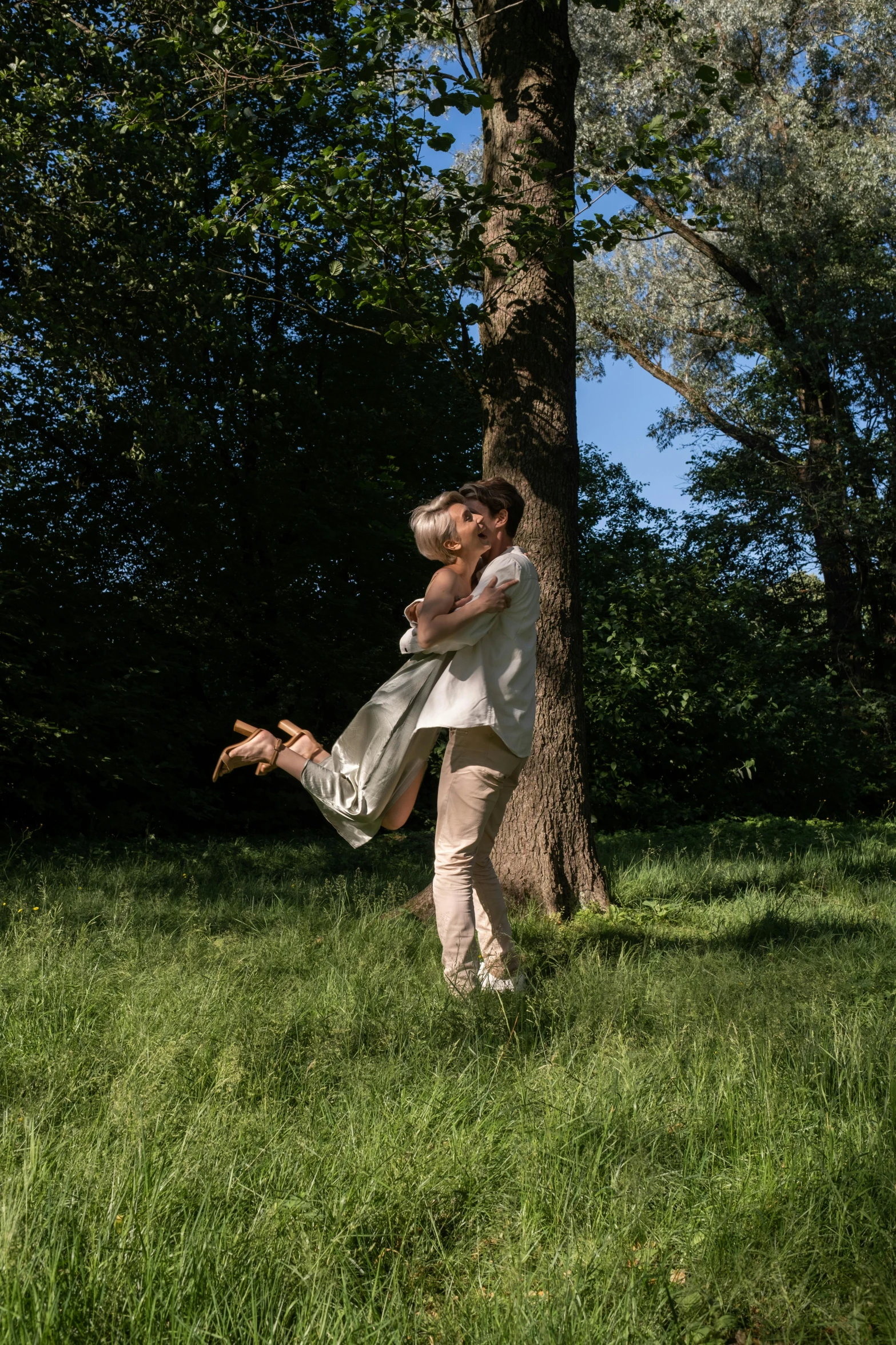 two people posing for pictures by a tree