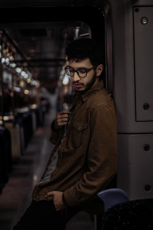 a man with glasses standing in front of a subway