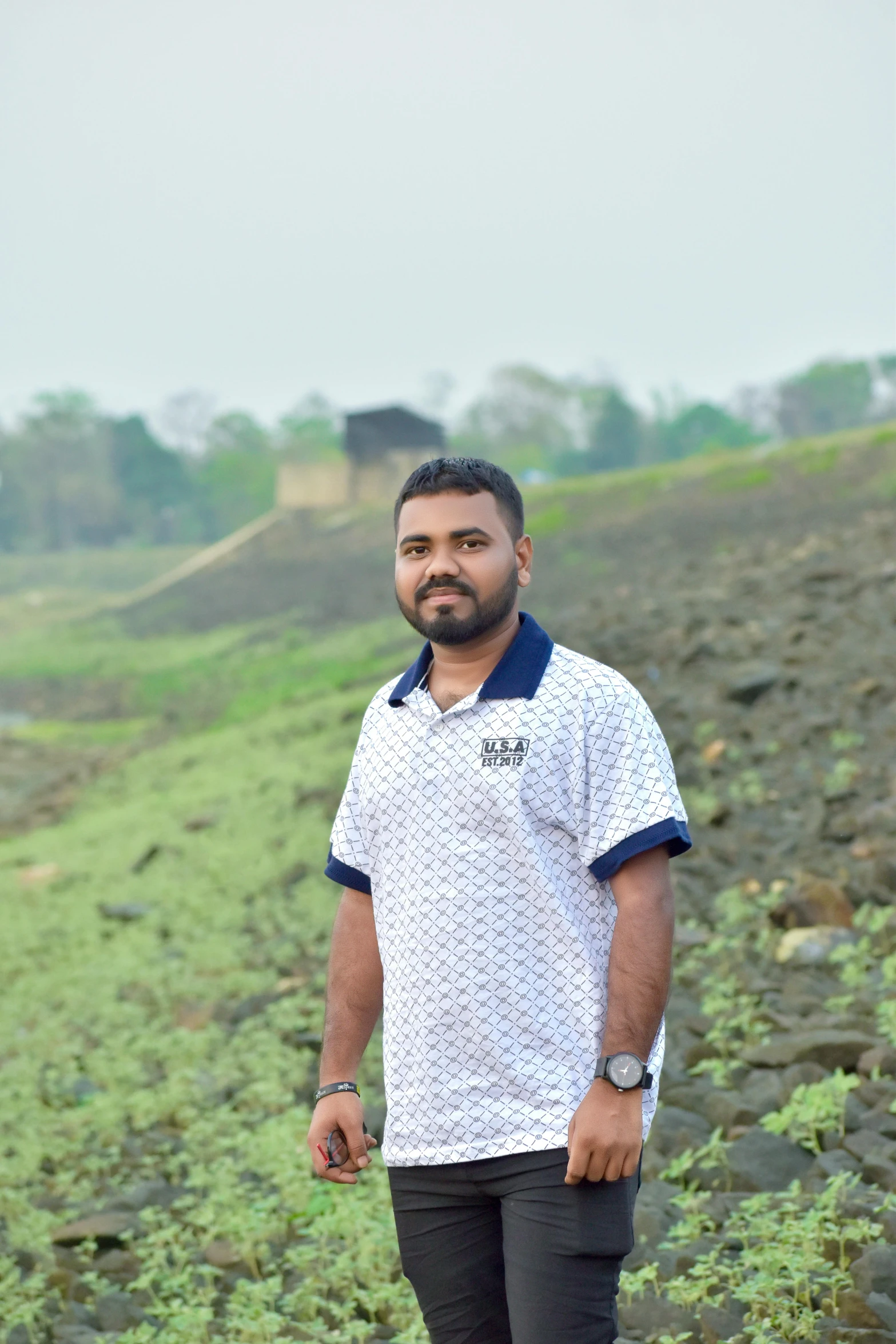 a man is standing in a field while wearing a white and blue shirt