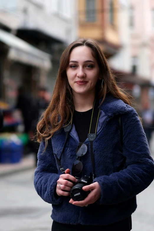a woman standing on a street holding onto a camera