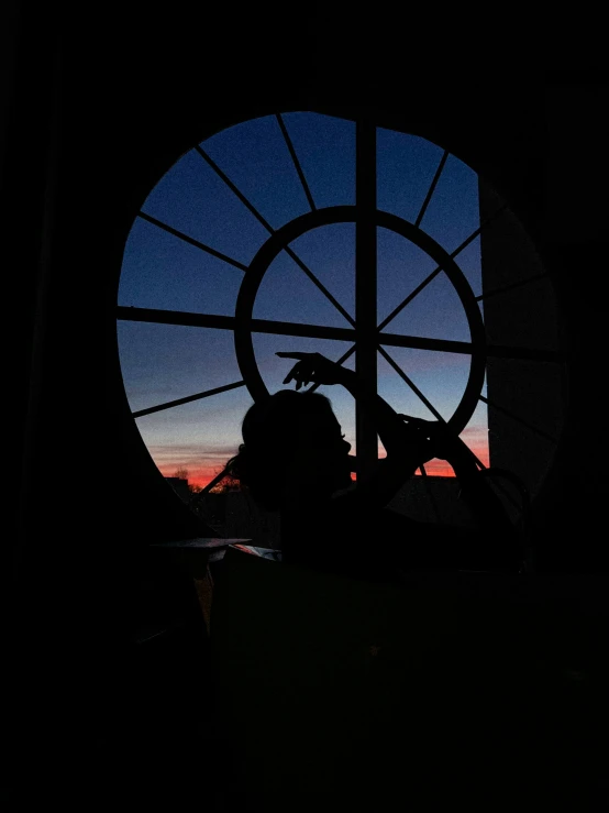 the silhouette of a woman is seen through a large circular window