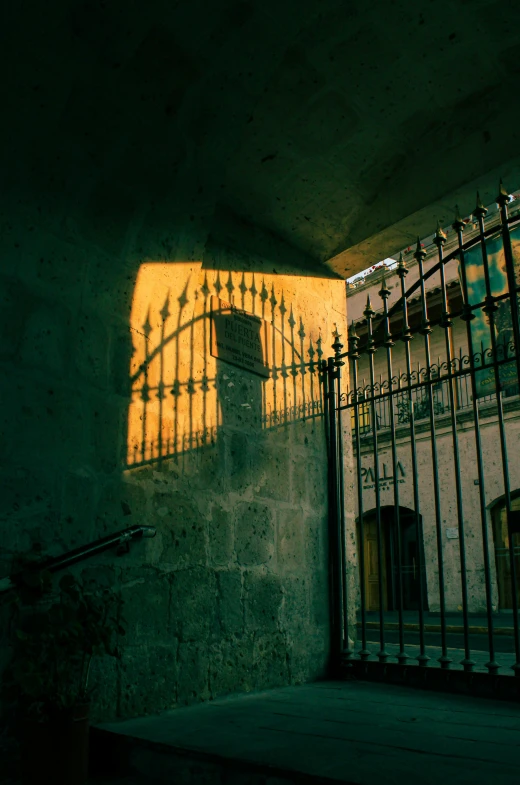 sunlight streaming through wrought iron gates casting shadows on a stone building