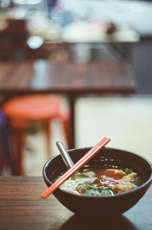 the noodles are in the bowl and there is a small pair of chop sticks in it