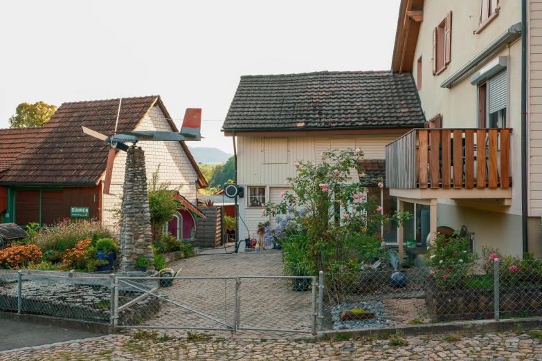 several houses with flowers around them in front of a chain link fence