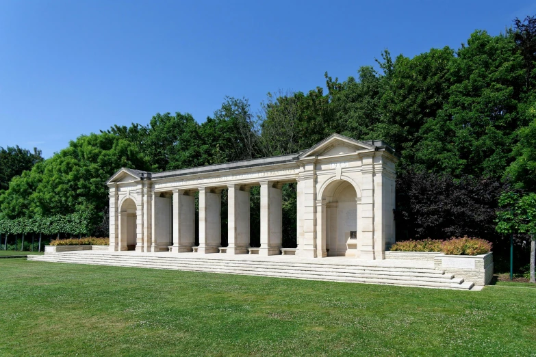 a group of white pillars sitting on top of a lush green park