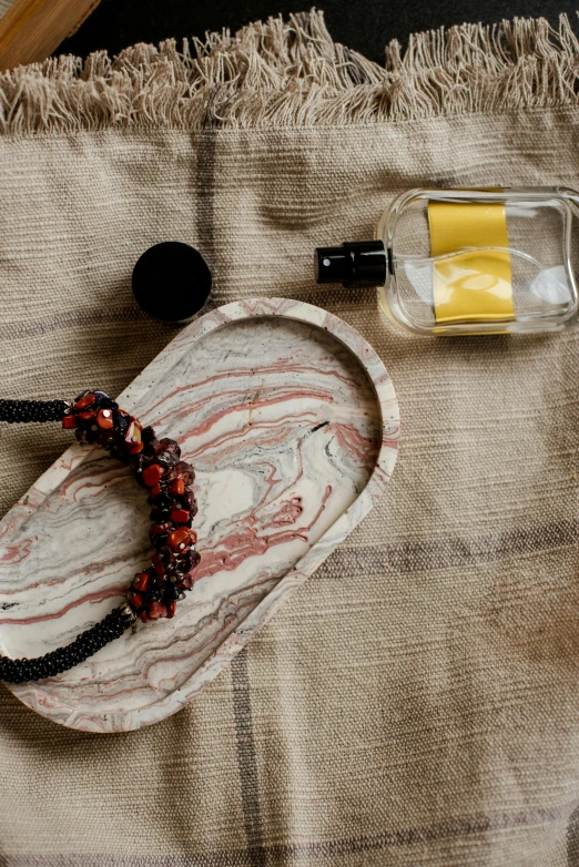 a stone, glass bottle and necklace on fabric