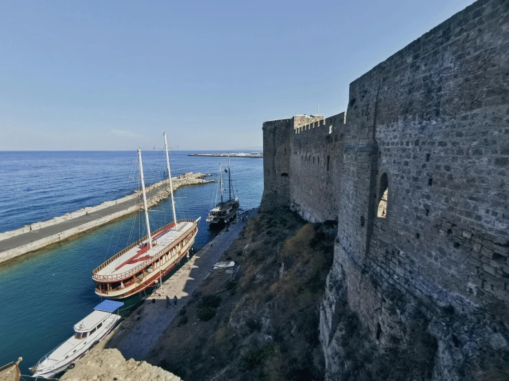 a boat docked in front of a stone castle wall