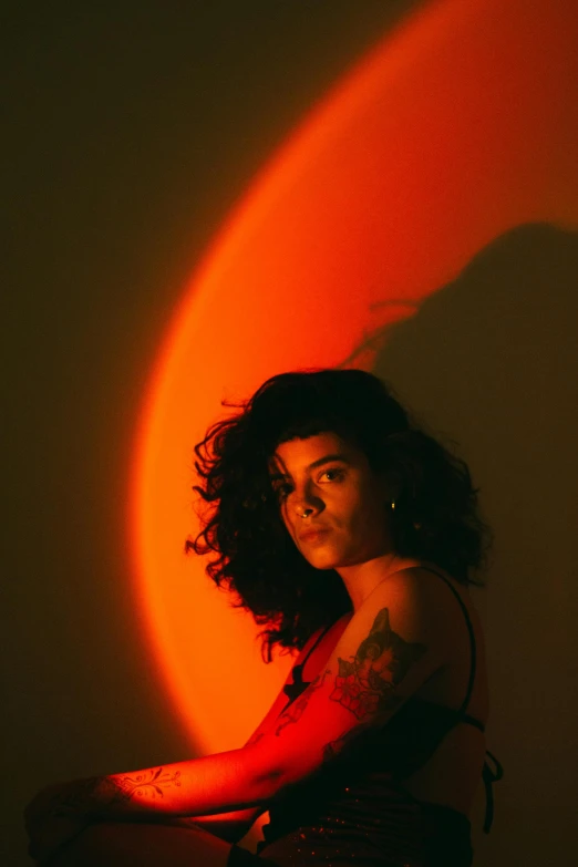 a woman with tattoos standing by a half - circle wall