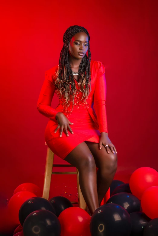 the woman sits on a stool next to balloons