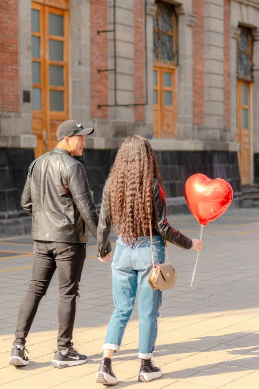 the man and the woman are holding a heart shaped balloon