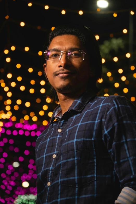 a man with glasses is standing in front of a wall of lights