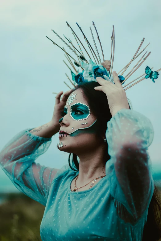 woman wearing blue and green make up and weird costume, looking at camera