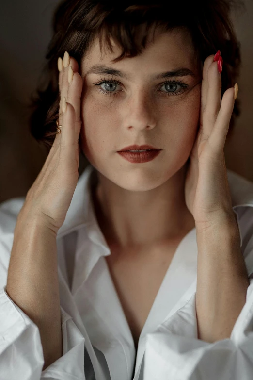 a woman with blue eyes, white blouse and gold rings