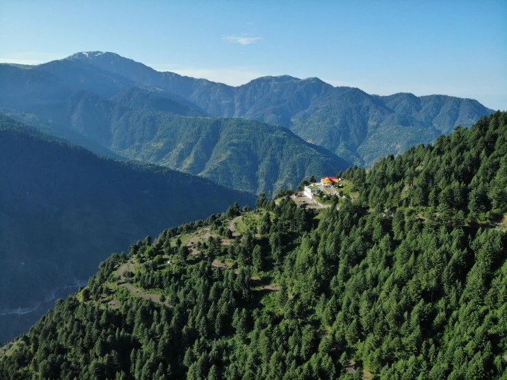 house in the middle of the mountain surrounded by evergreen trees