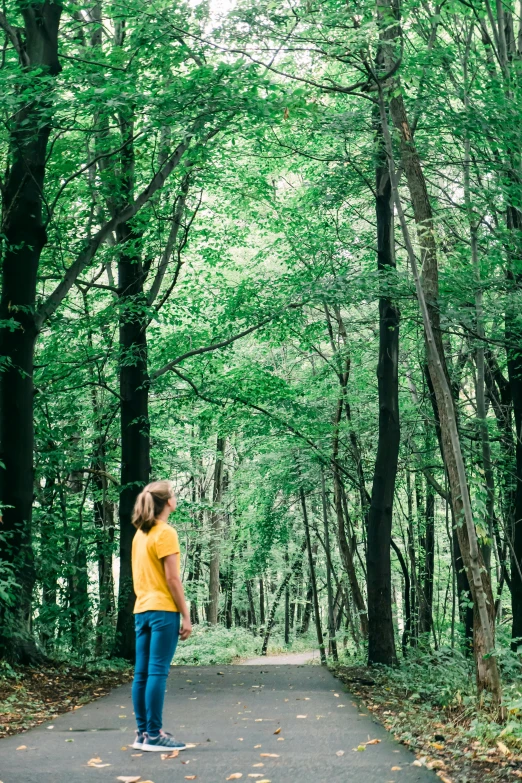 a  standing in a wooded area while wearing a yellow shirt