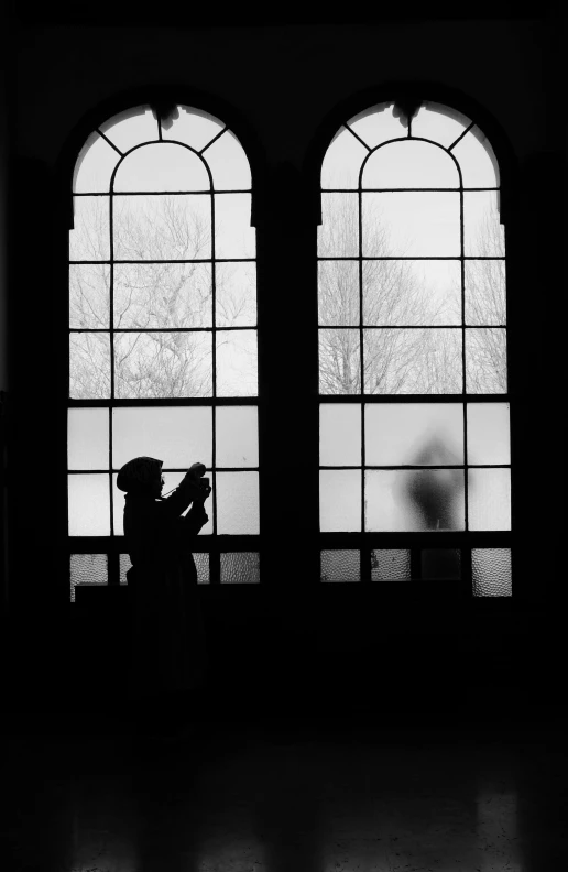 a person holding an umbrella in front of two large windows