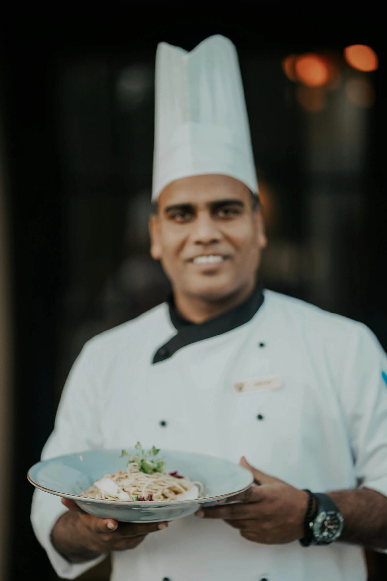 a chef is holding up a plate of food