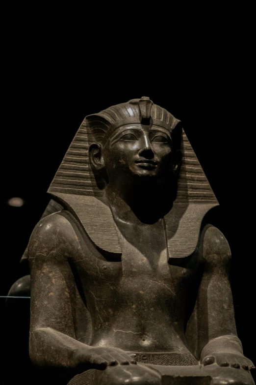 an egyptian statue with a clock in its lap