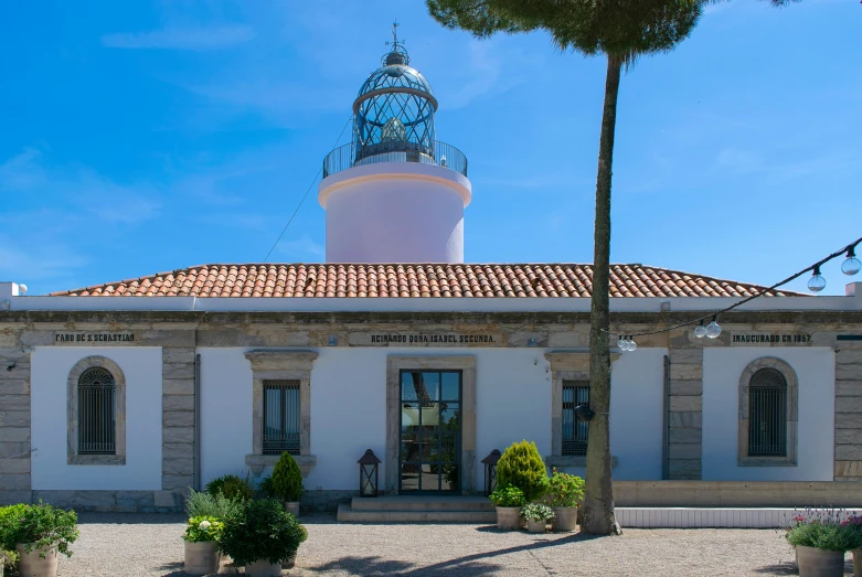 a white lighthouse with some trees and bushes