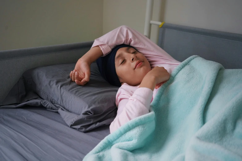 a woman lays on the bed with her head under a blanket