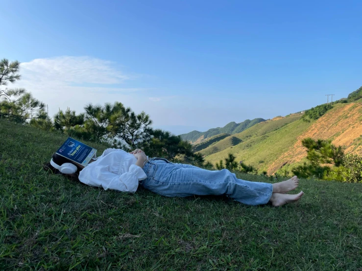 a person that is laying in the grass reading