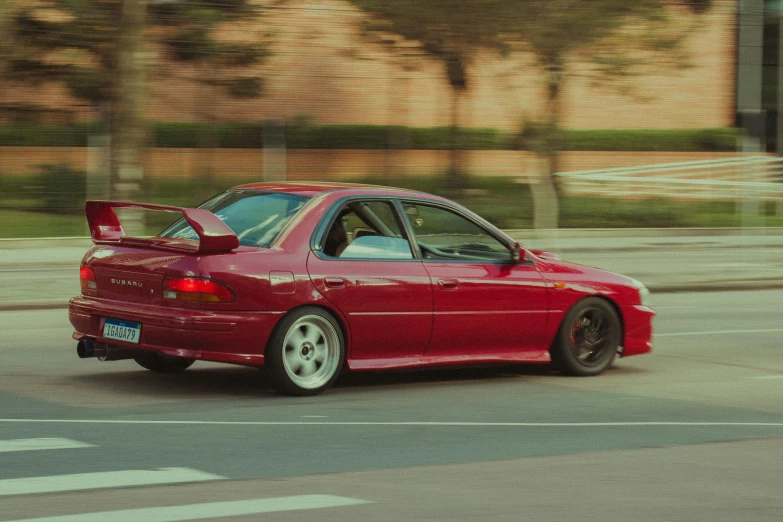 this is a picture of a red car driving down the street