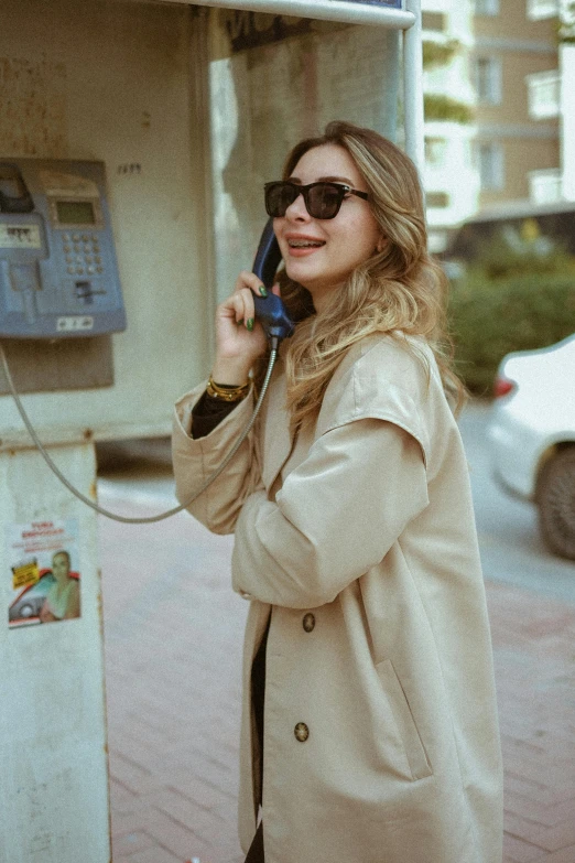 a woman stands in front of a parking meter, talking on a cell phone