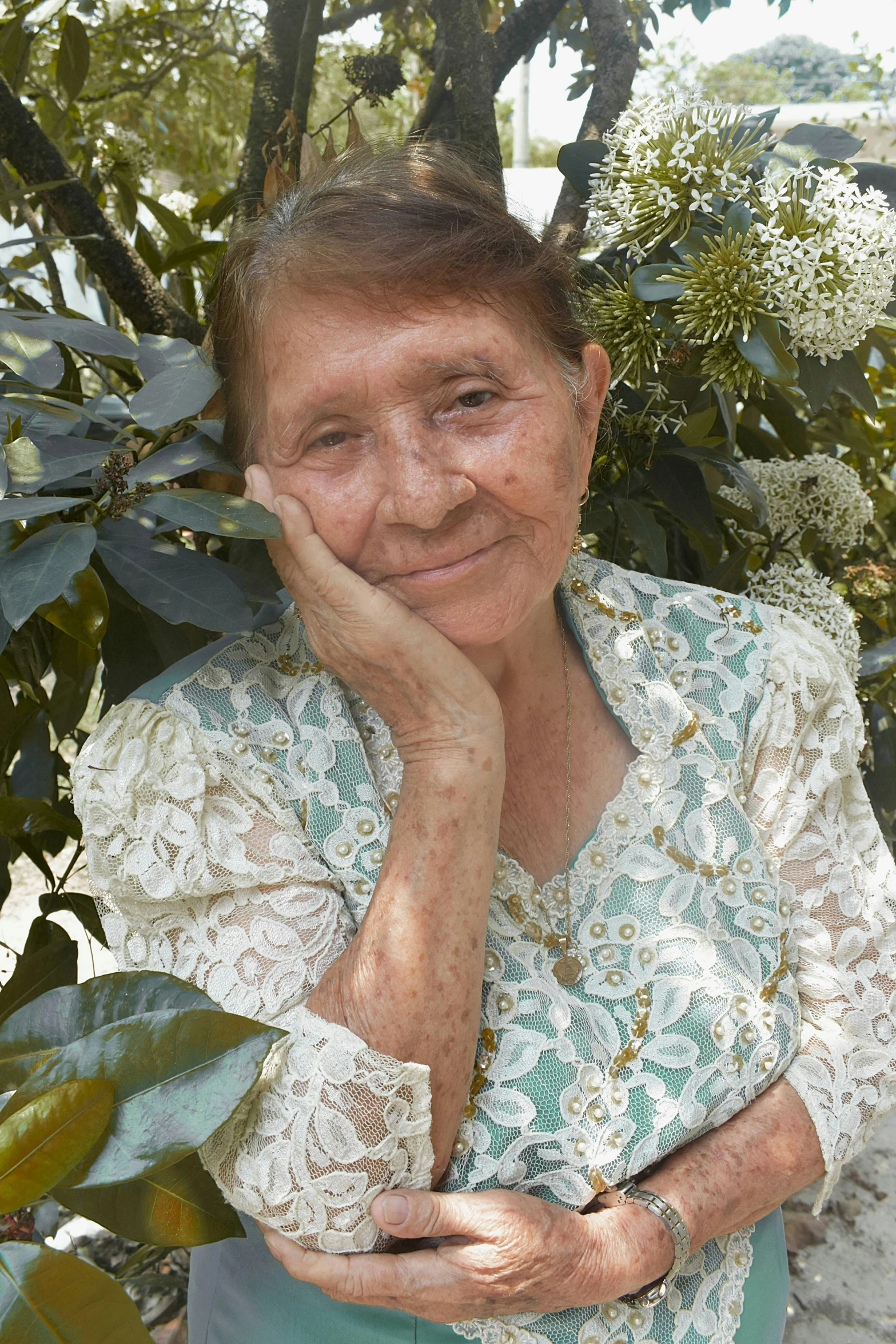 an older woman wearing glasses smiling with her hands crossed