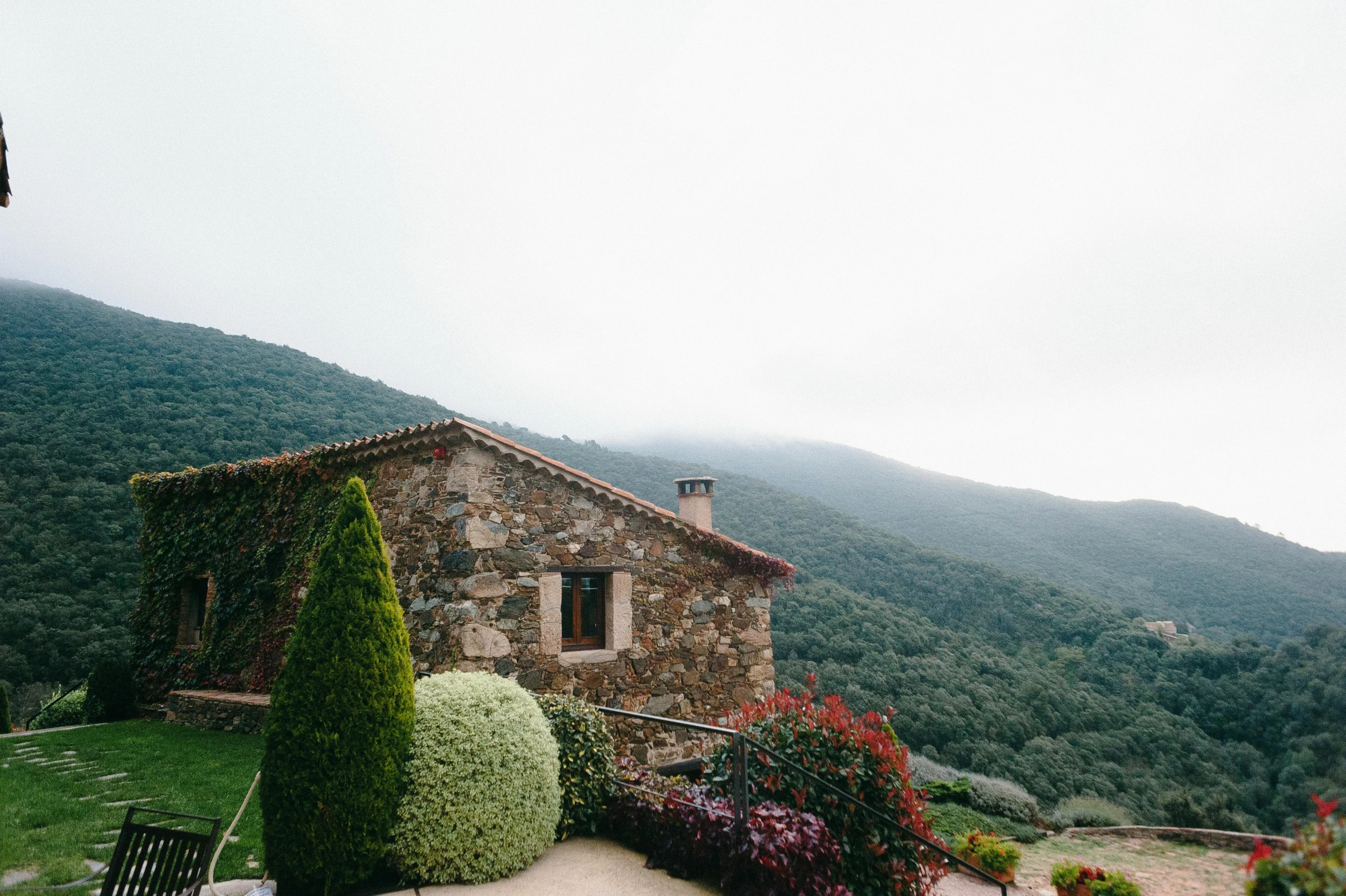 a stone building sitting between two green trees