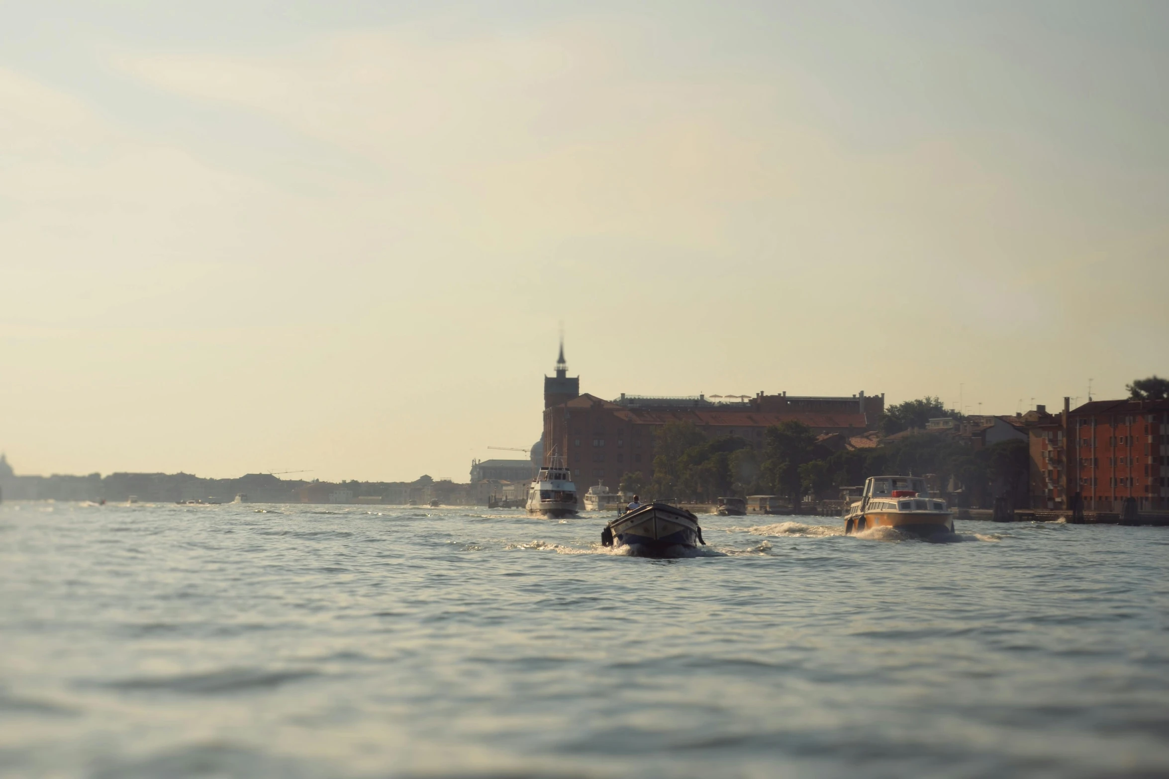 three boats are moving on the water in front of a castle