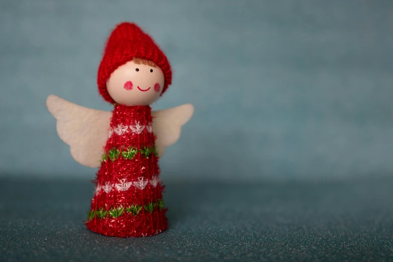 a small red angel in a knitted sweater on the ground