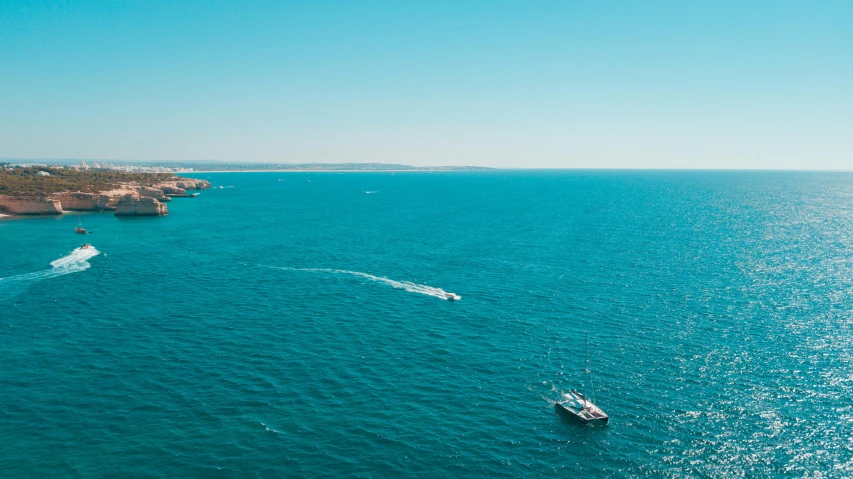 a lone boat sailing along the coast of blue water