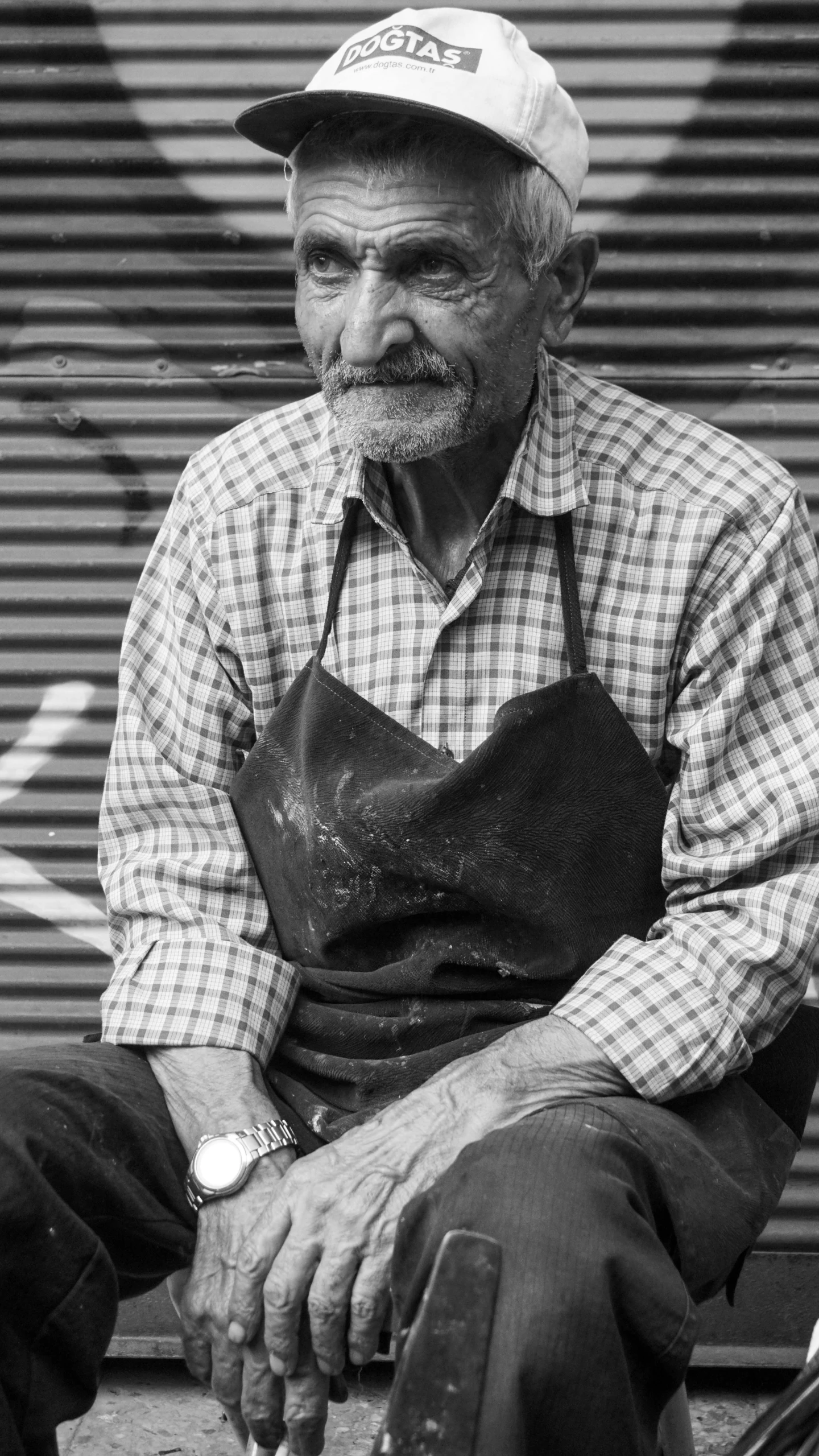 an old man with an apron sitting in front of a garage door