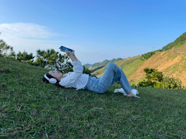 a person on a hill laying down holding up their shoes