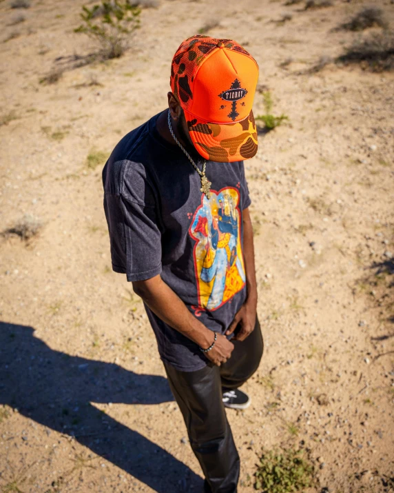 a man stands in the desert wearing an orange hat